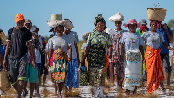 Eden People+Planet community gathering with diverse women in traditional attire planting trees outdoors.